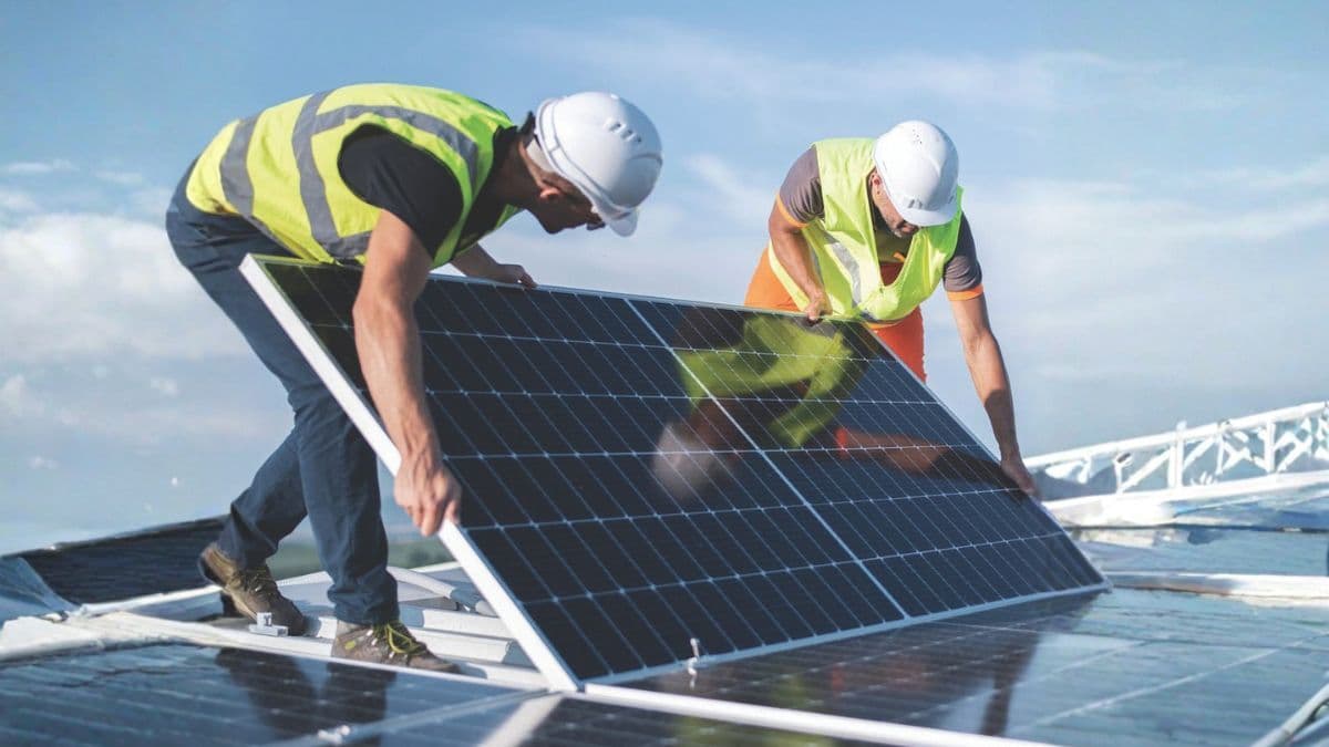 Technicians install solar panels, reflecting the rapid scale-up of renewable energy infrastructure.